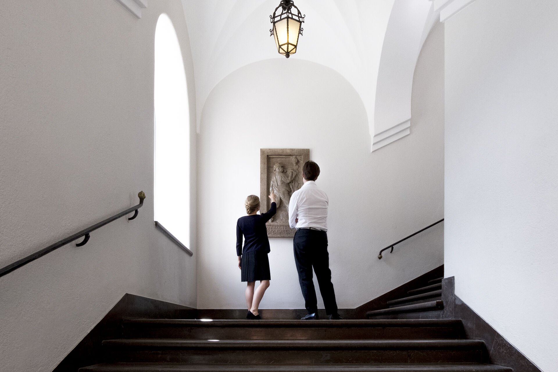 Pampig stentrappa inne i Röhsska museet, på trappavsatsen står en man och en kvinna och tittar på ett donerat konstverk.
